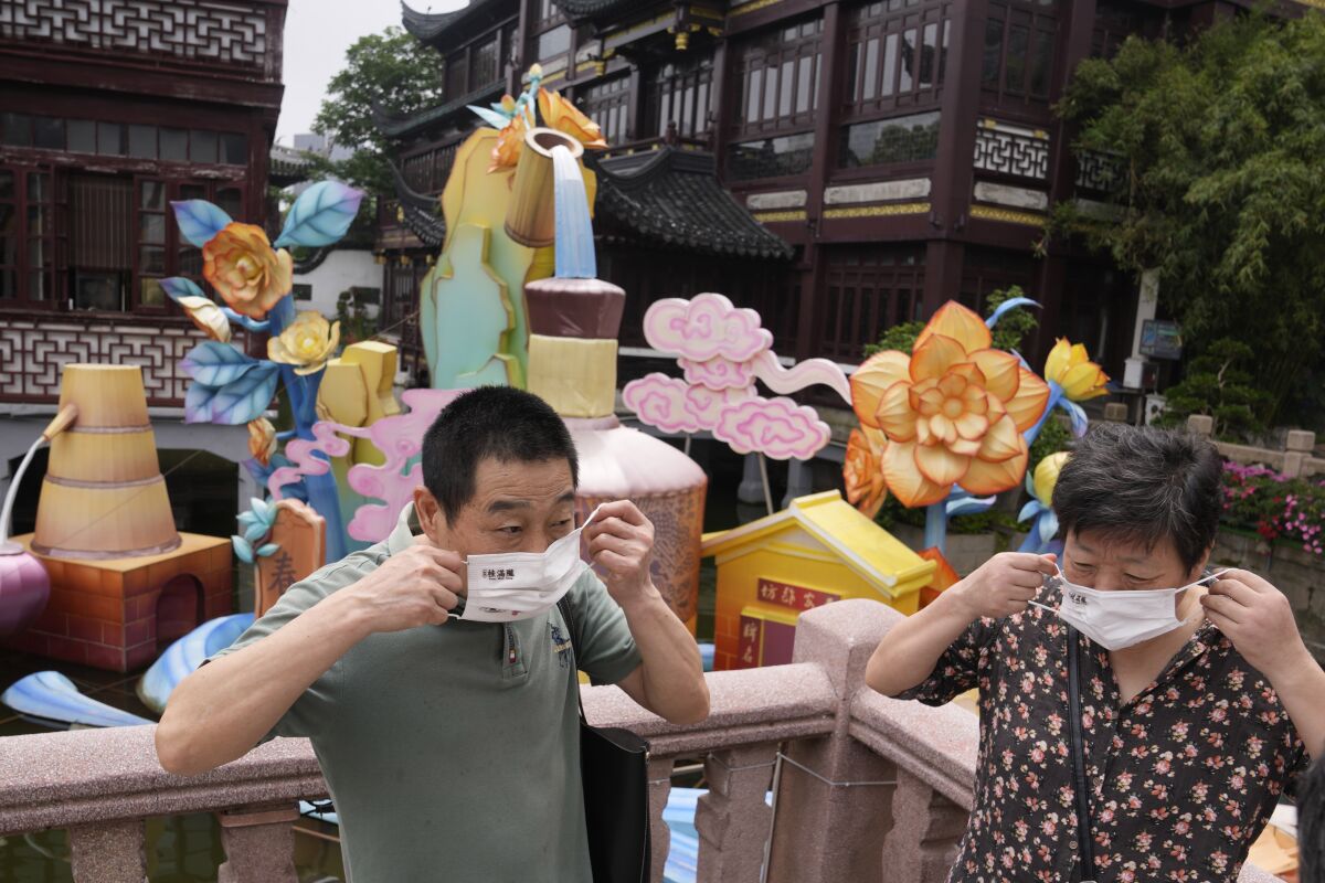 Visitors to the Yu Garden Mall put their masks on after posing for photos, Thursday, June 2, 2022, in Shanghai. Traffic, pedestrians and joggers reappeared on the streets of Shanghai on Wednesday as China's largest city began returning to normalcy amid the easing of a strict two-month COVID-19 lockdown that has drawn unusual protests over its heavy-handed implementation. (AP Photo/Ng Han Guan)