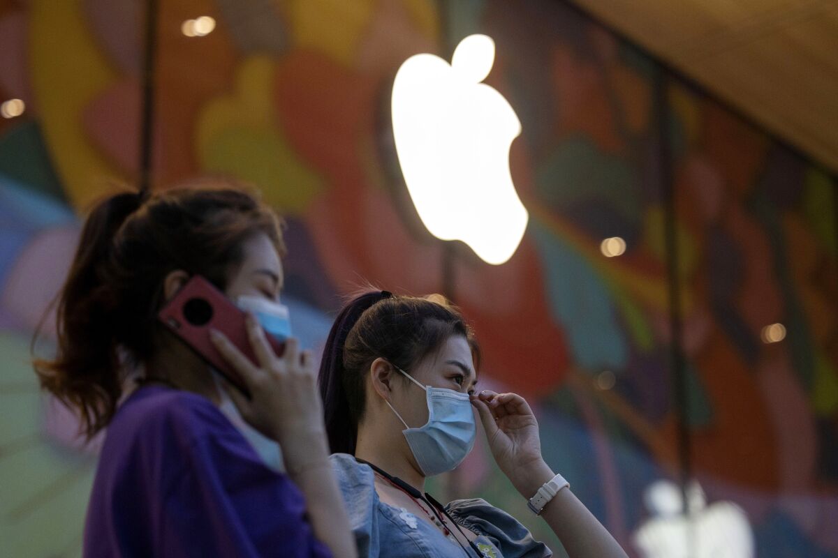 Women stand near new Apple store in Beijing