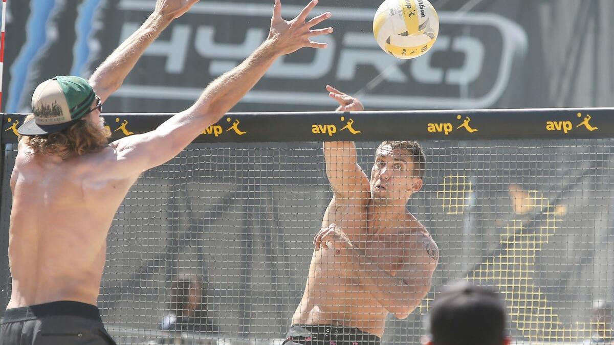 Trevor Crabb puts the ball past the block of Jeremy Casebeer during day two of the AVP Huntington Beach Open at the Huntington Beach pier on Saturday