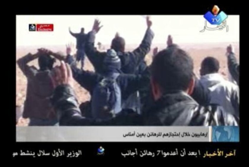 In this image made from video, a group of people believed to be hostages kneel in the sand with their hands in the air at an unknown location in Algeria. Algerian de-mining teams were scouring a gas refinery on Sunday, Jan. 20, 2013 that was the scene of a bloody four-day standoff, searching for explosive traps left by the Islamist militants who took dozens of foreigners hostage. The siege left at least 23 captives dead, and the American government warned that there were credible threats of more kidnapping attempts on Westerners. (AP Photo/Ennahar TV) ALGERIA OUT, TV OUT