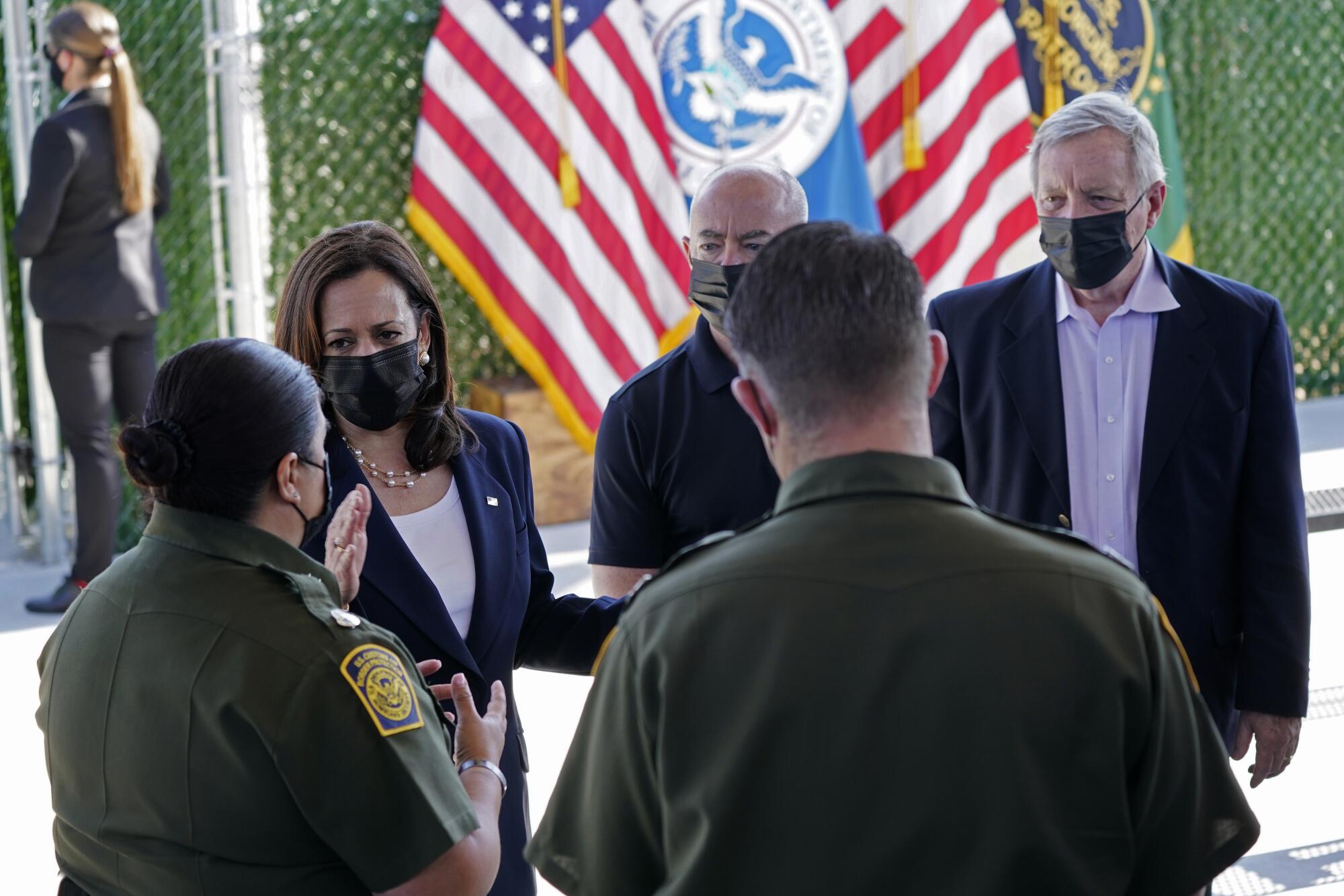 Vice President Kamala Harris, second from left, wears a mask while talking to a Border Patrol official in El Paso