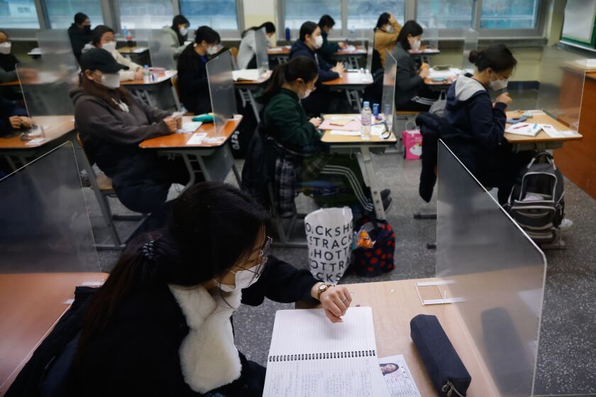 A student checks the time as others wait for the start of the annual college entrance examination amid the coronavirus pandemic at an exam hall in Seoul, South Korea, Thursday, Dec. 3, 2020. South Korean officials are urging people to remain at home if possible and cancel gatherings as about half a million students prepare for a crucial national college exam. (Kim Hong-Ji/Pool Photo via AP)