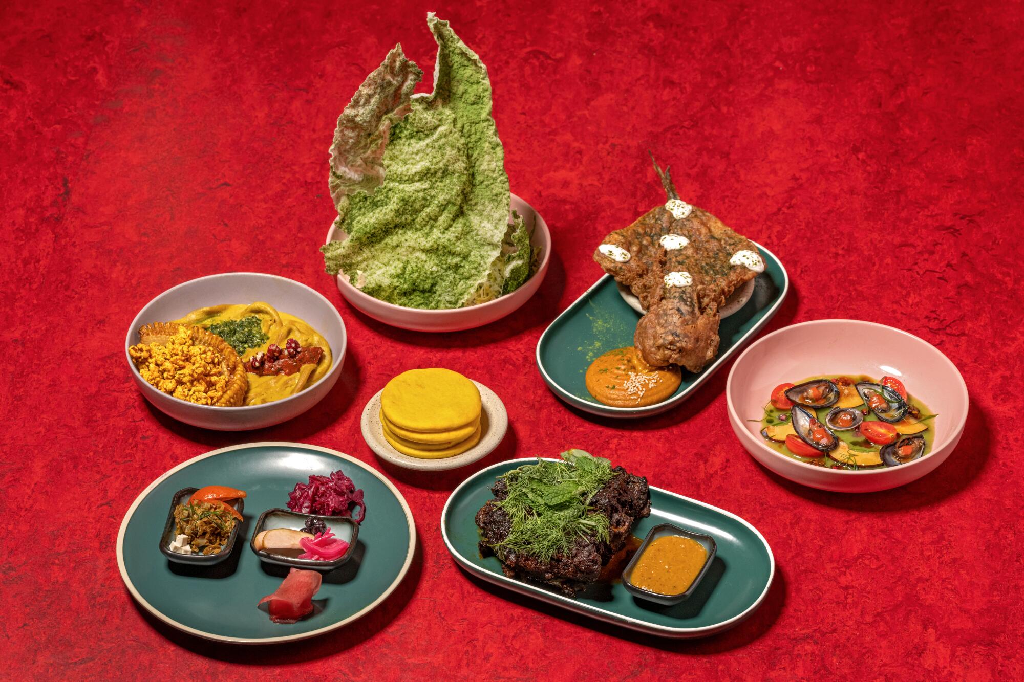 A spread of dishes at Poltergeist against a red background. 