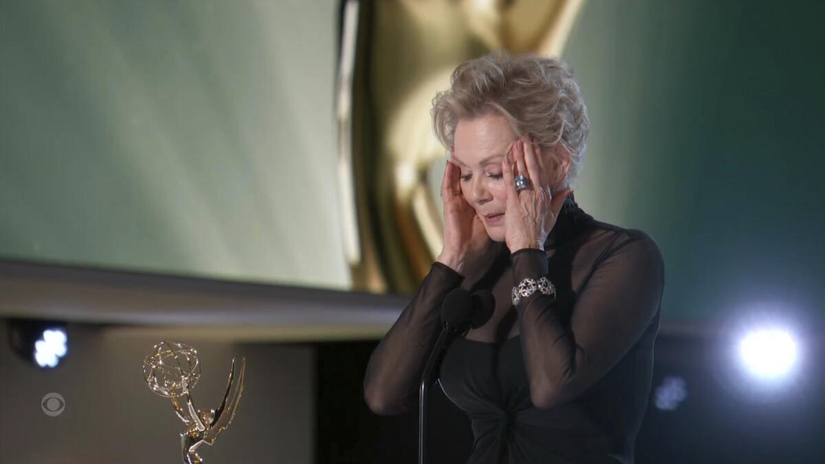 A woman holds her hands to her temples onstage