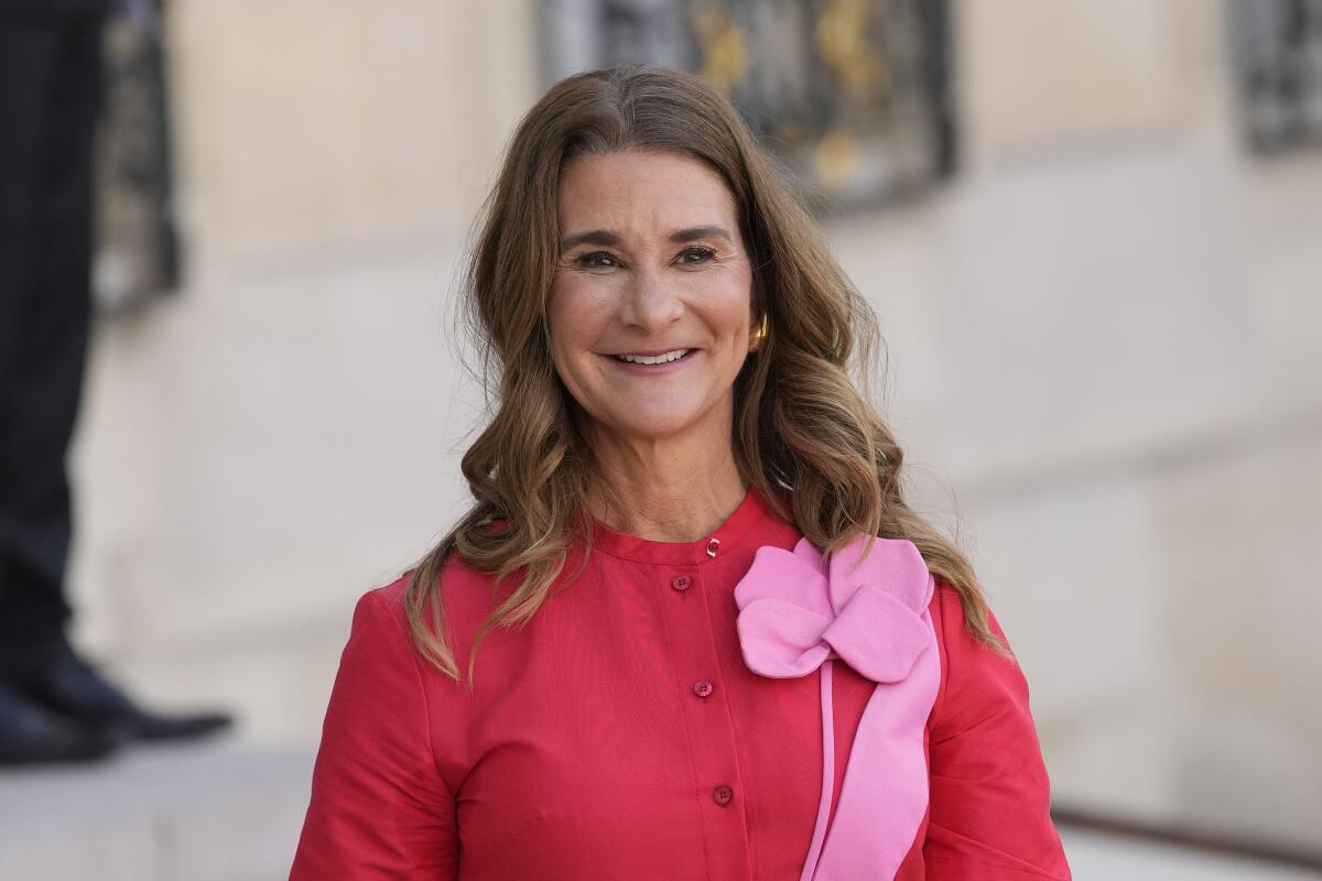 Melinda French Gates smiles while wearing a red and pink outfit.