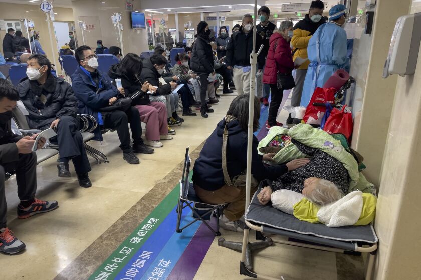 A woman looks after her elderly relative lying on a stretcher as patients receive intravenous drips in the emergency ward of a hospital in Beijing, Thursday, Jan. 5, 2023. Patients, most of them elderly, are lying on stretchers in hallways and taking oxygen while sitting in wheelchairs as COVID-19 surges in China's capital Beijing. (AP Photo/Andy Wong)
