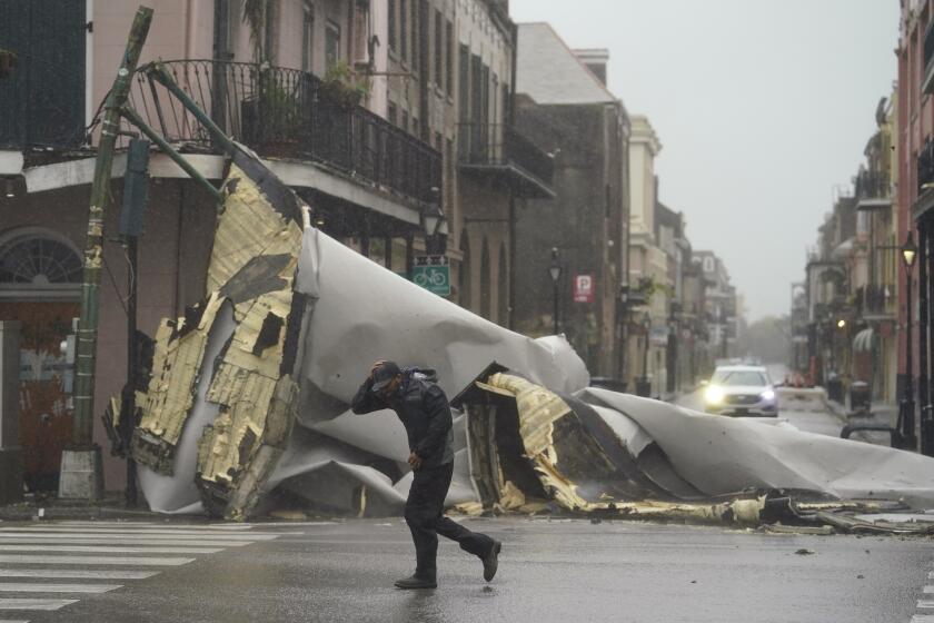 A man passes by a section of roof that was blown off of a building in the French Quarter by hurricane winds in New Orleans. 