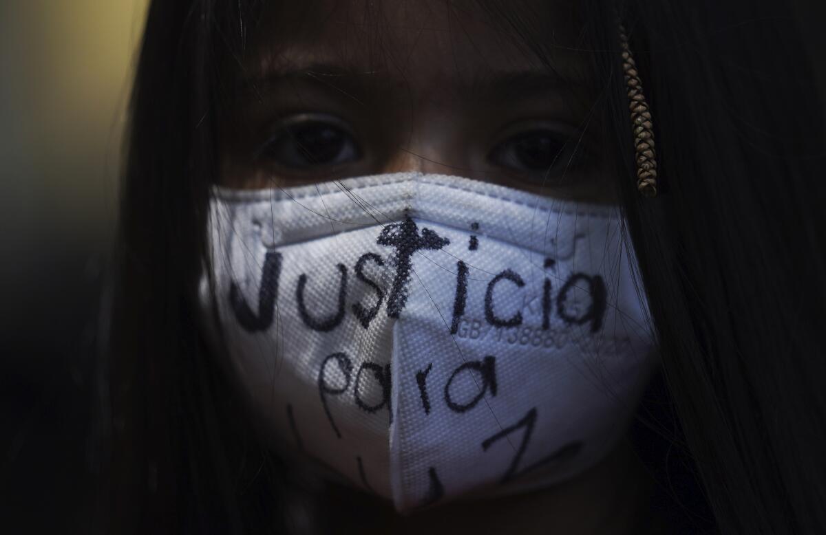 Una niña usa una máscara con la frase "Justicia para Luz", escrita en español, 