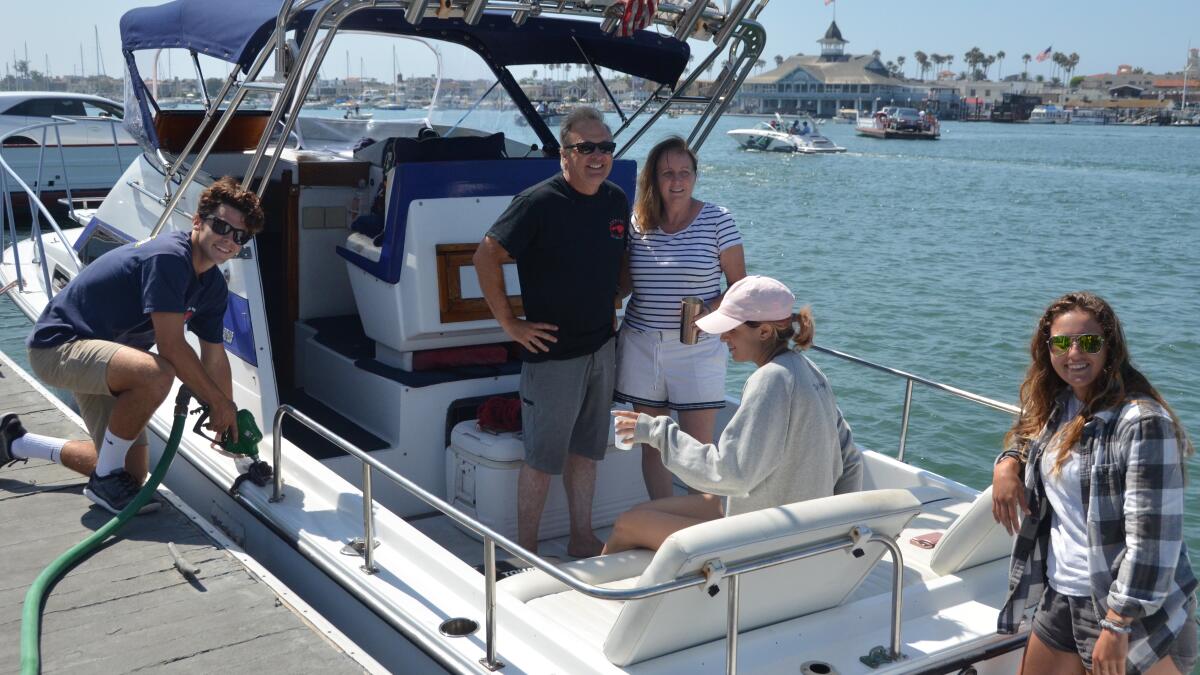 Island Marine Fuel employee Jake Hamilton fuels the Skiptown for, from center left, Michael and Tamerra Jarvis, Madison Arena and Lauren Douglas.