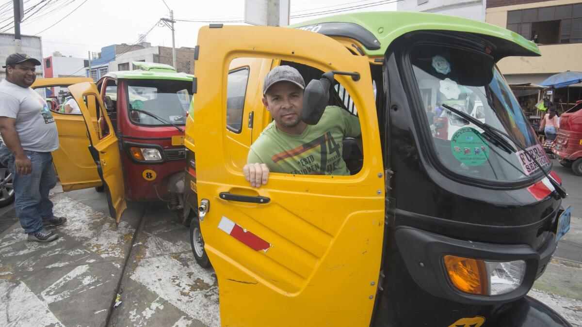 Wilfredo Arceno, foreground, in his "mototaxi" in Lima, Peru.