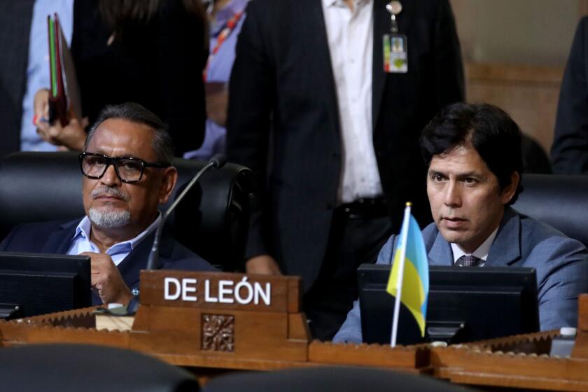 LOS ANGELES, CA - OCTOBER 11: Councilmember District 1 - Gil Cedillo, left, and Councilmember District 14 - Kevin de Leon, right, at the Los Angeles City Council meeting at Los Angeles City Hall on Tuesday, Oct. 11, 2022 in Los Angeles, CA. Protestors want the resignation of Los Angeles Councilmembers Nury Martinez, Kevin de Leon and Gil Cedillo. Martinez made racist remarks about Councilmember Mike Bonin son in the recording as her colleagues, Councilmembers Kevin de Leon and Gill Cedillo, laughed and made wisecracks. (Gary Coronado / Los Angeles Times)