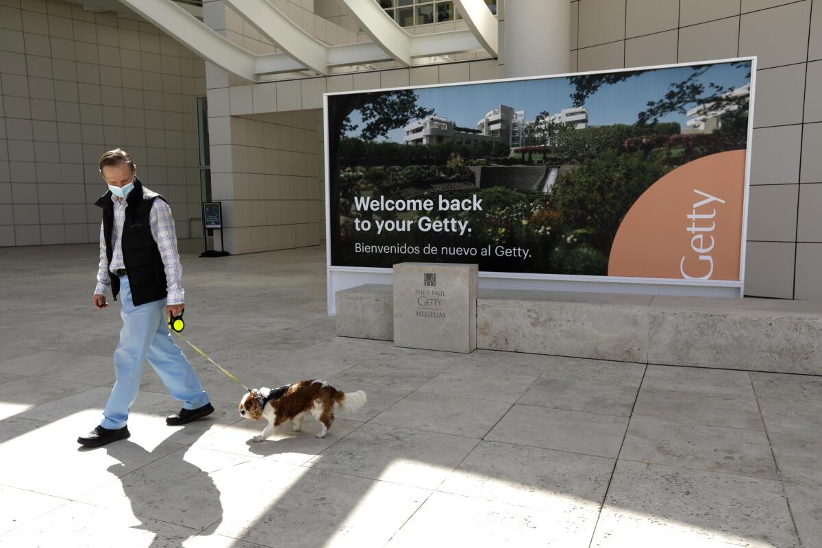 A man walking his dog wears a mask outside the Getty Center in Los Angeles. 