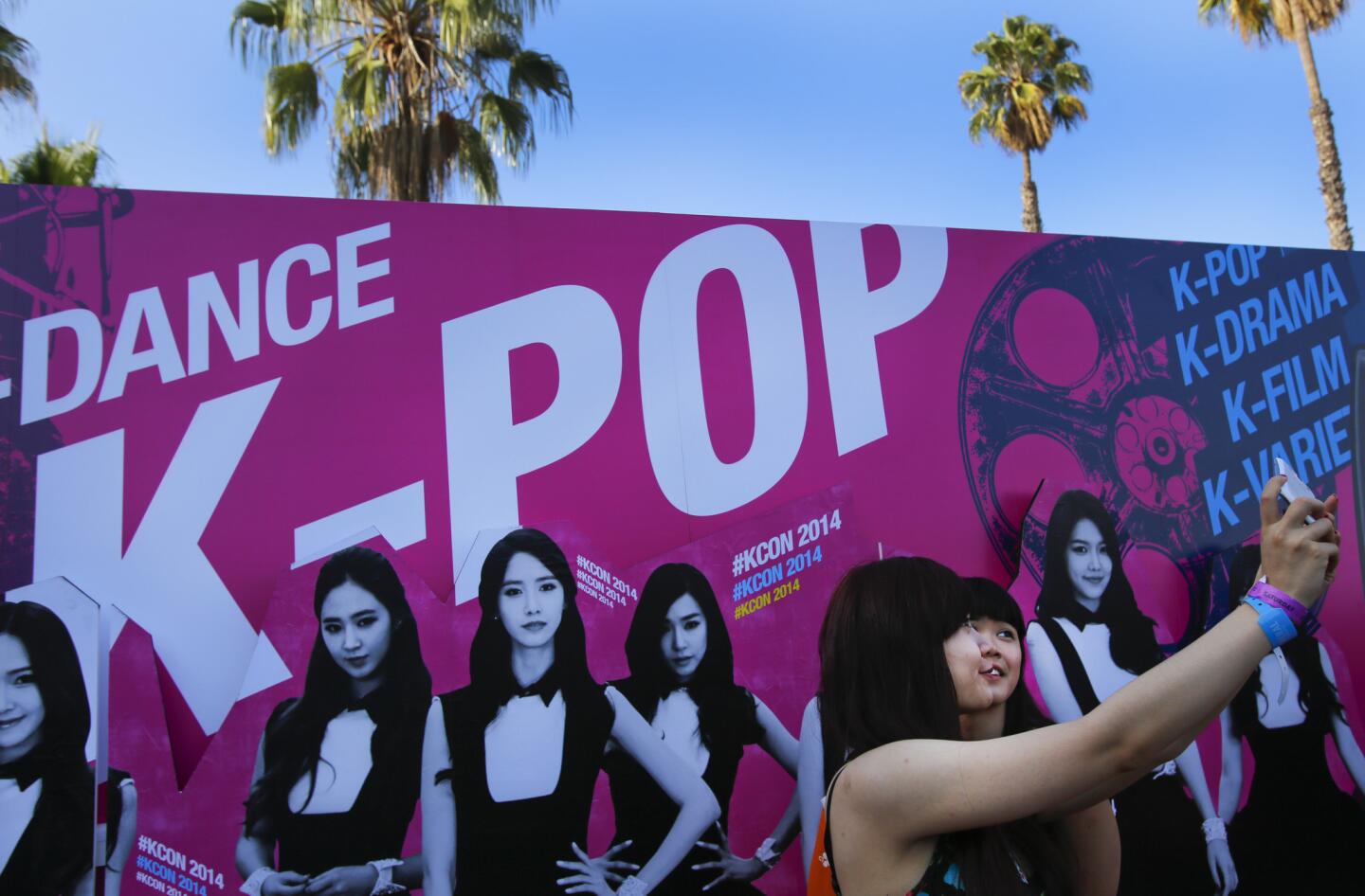 The K-pop convention took place at the Los Angeles Sports Arena on Saturday evening, bringing Korean pop music fans together from far and wide. Nancy Huynh, right, and Jina Tran pose for a "selfie" in front of a banner promoting some of the acts performing at the KCON concert at the Sports Arena.