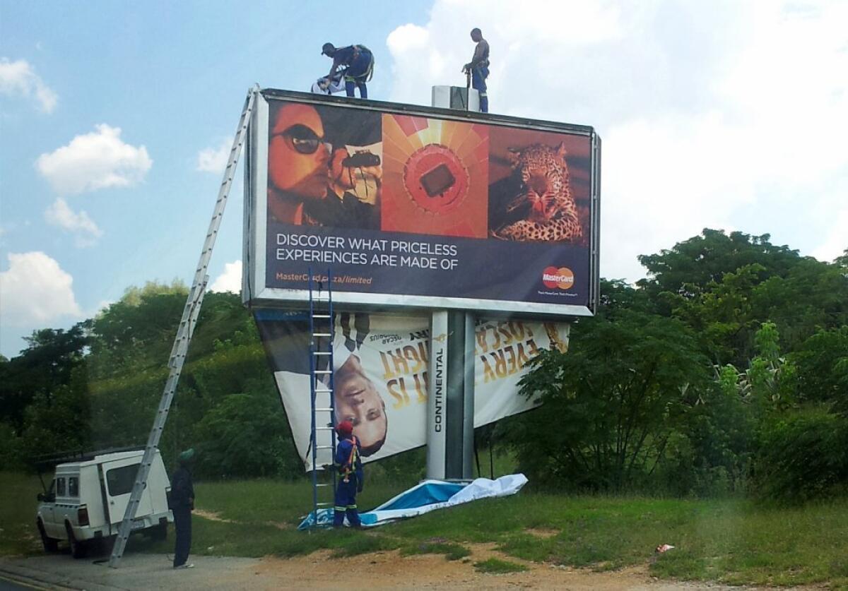 Workers take down a billboard of Olympic athlete Oscar Pistorius endorsing a product in Johannesburg, South Africa, hours after he was charged with murder.