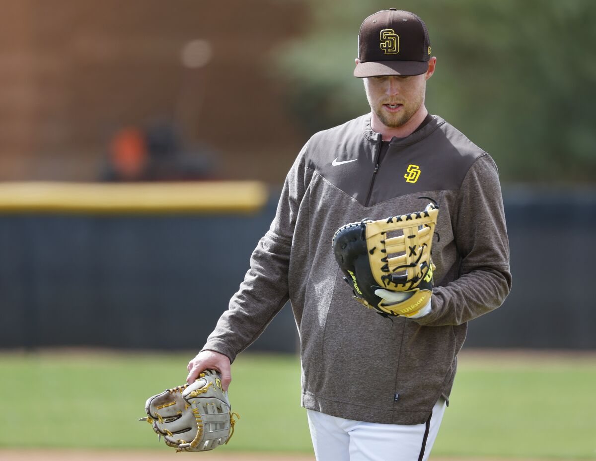  Jake Cronenworth looks at his first baseman's mitt during a Feb. 22 workout. 