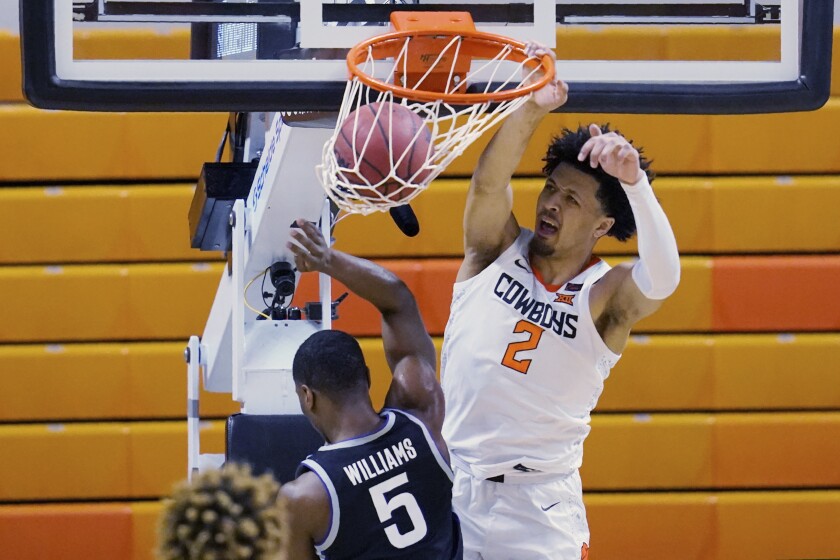 Oklahoma State guard Cade Cunningham (2) dunks in front of Kansas State guard Rudi Williams (5) in the first half of an NCAA college basketball game Saturday, Feb. 13, 2021, in Stillwater, Okla. (AP Photo/Sue Ogrocki)