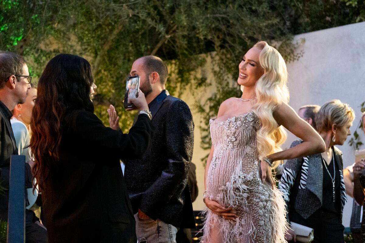 A pregnant woman in a dramatic gown poses for a photo at a party