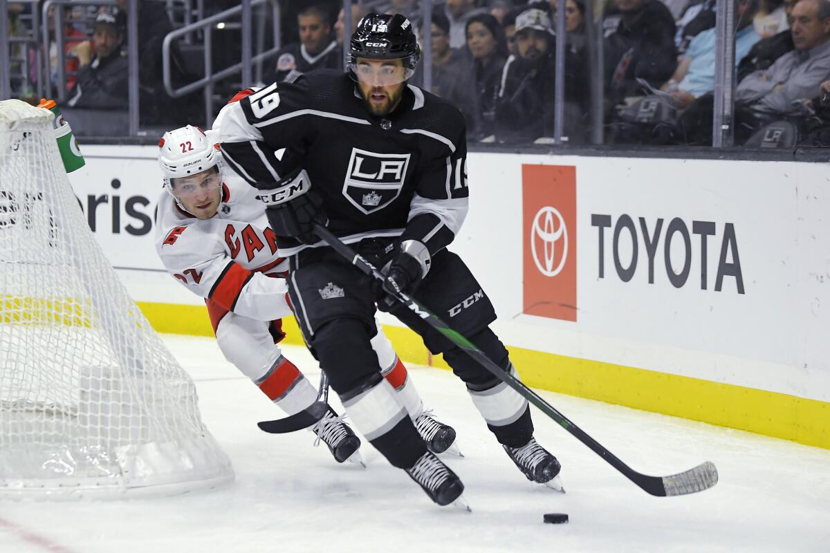 Kings left wing Alex Iafallo, right, moves the puck while under pressure from Carolina Hurricanes defenseman Brett Pesce during the second period on Tuesday at Staples Center.