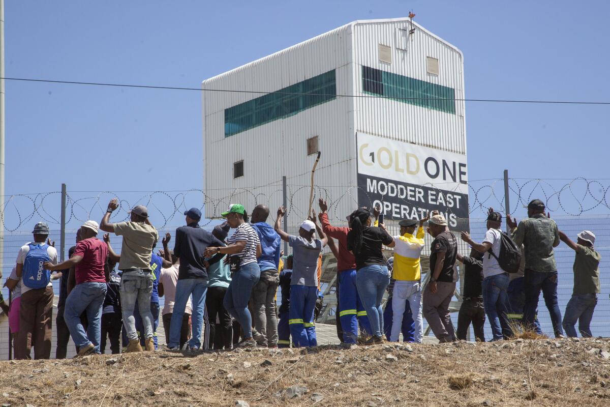 A group of miners stand around a fence.