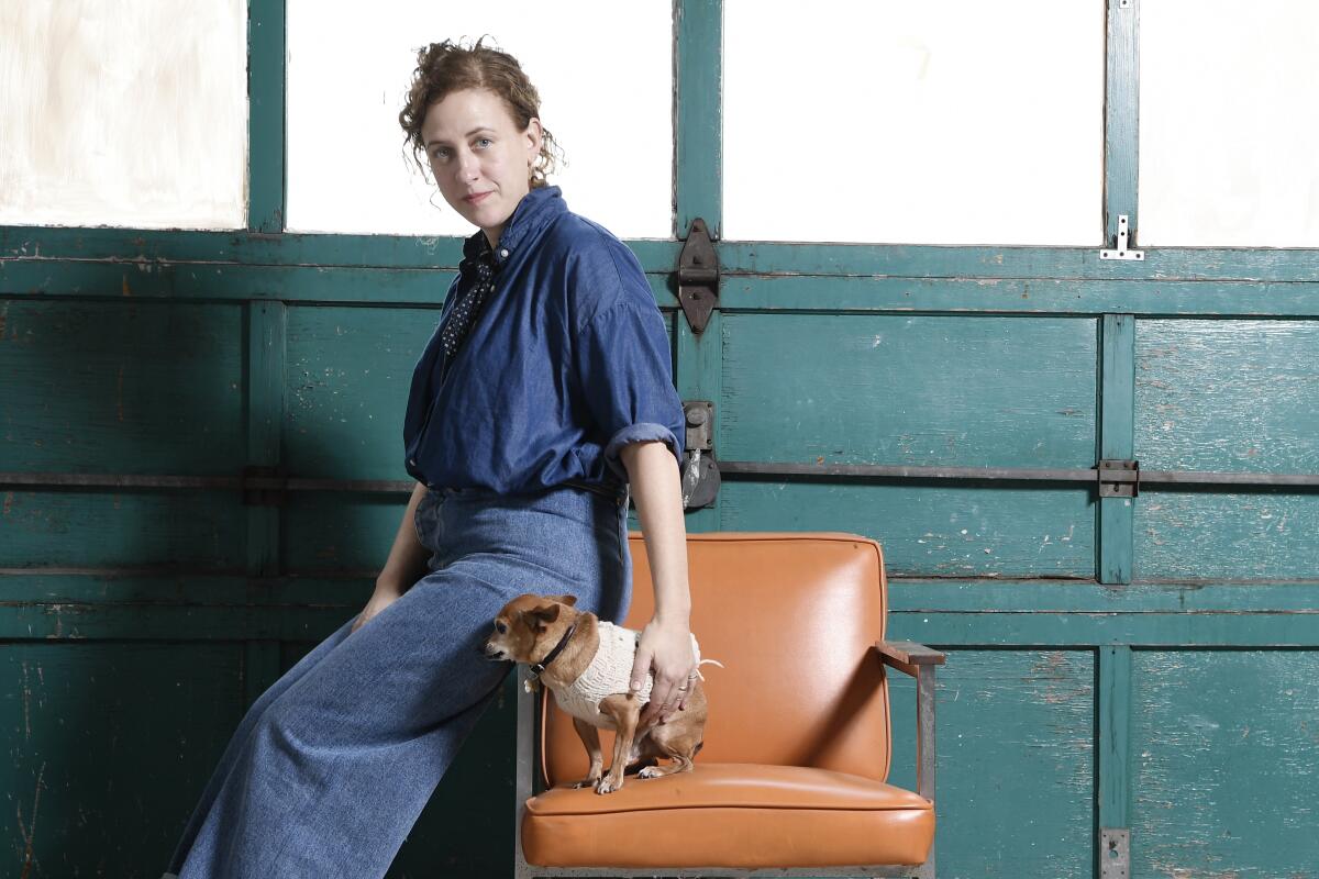 Ceramist Heather Levine sits on the arm of a chair occupied by her shop dog, Pierre.