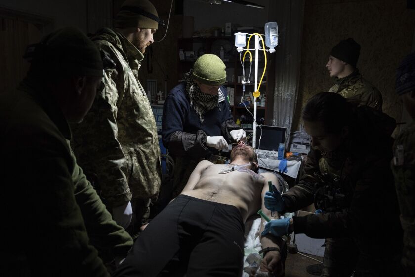 Ukrainian military medics treat their wounded comrade at a field hospital near Bakhmut, Ukraine, Wednesday, March 1, 2023. (AP Photo/Evgeniy Maloletka)