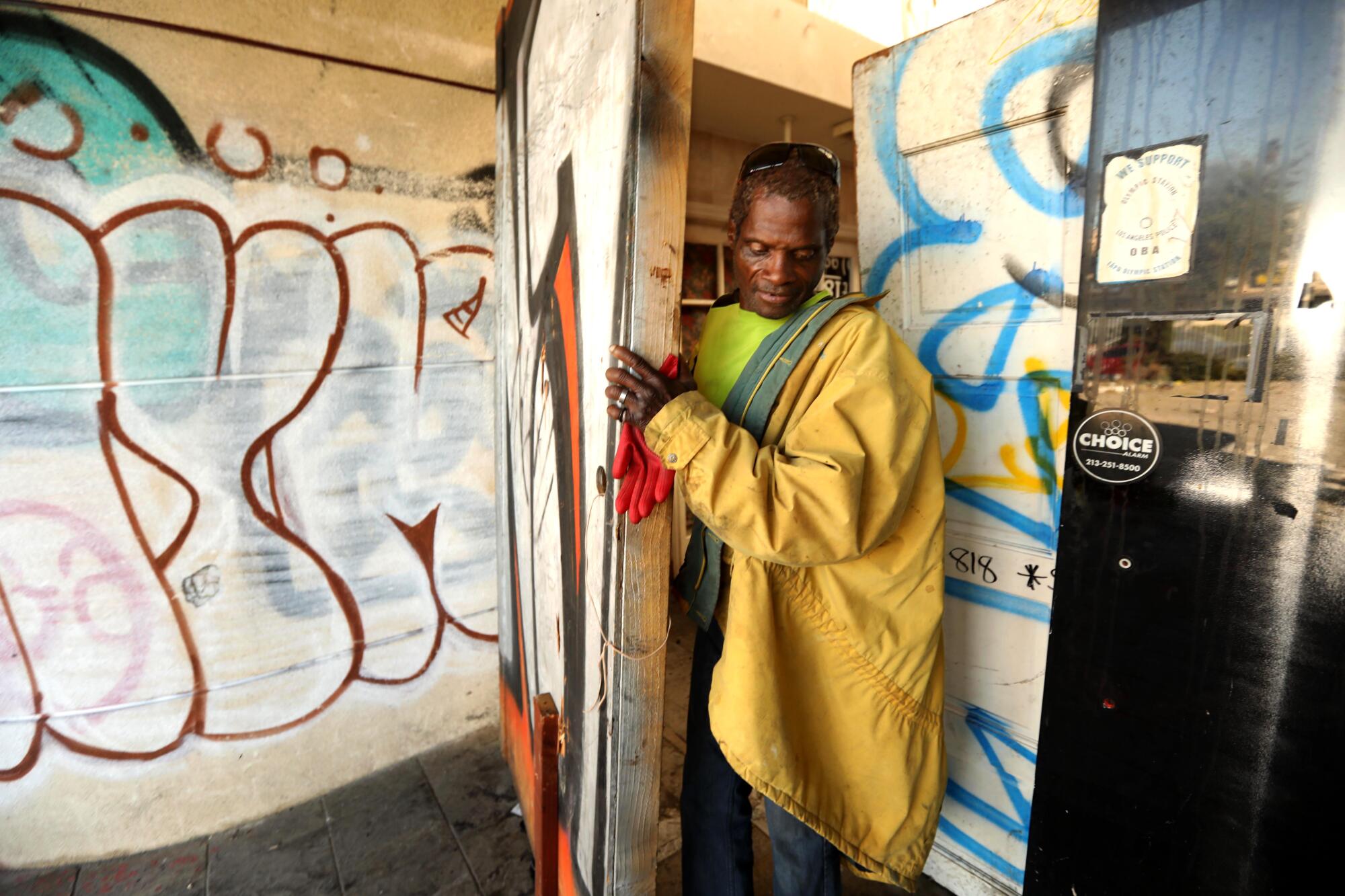 A man walks through a door into a room covered with graffiti