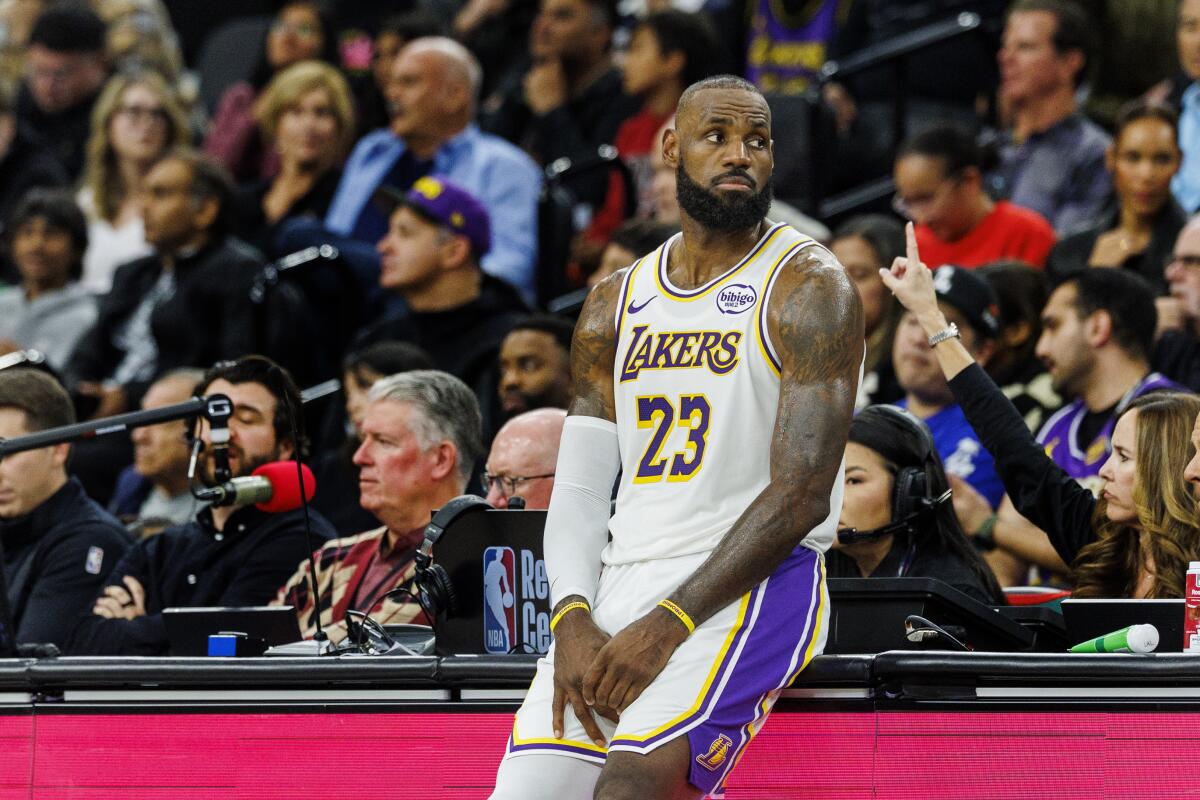Lakers forward LeBron James leans against the scorer's table as he wait to check into a game.