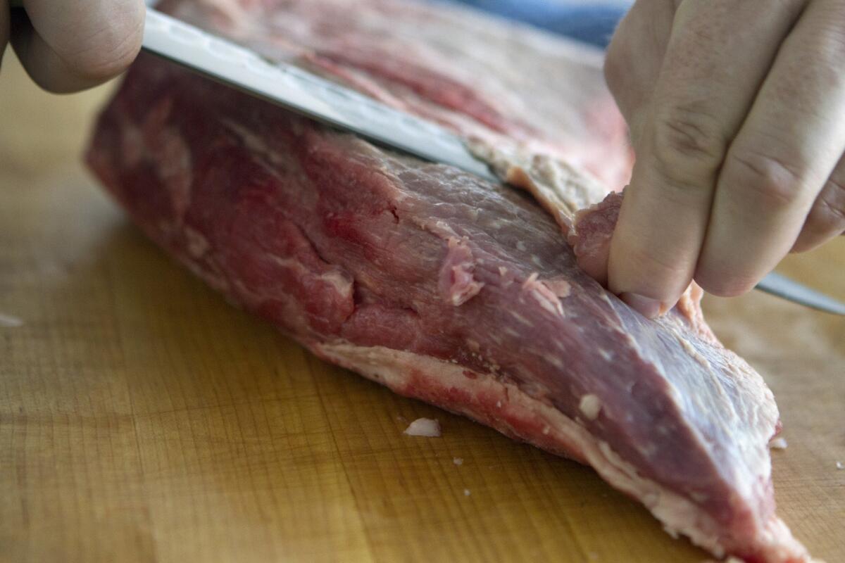 Barrel & Ashes chef Tim Hollingsworth trims off the fat on his tri-tip.