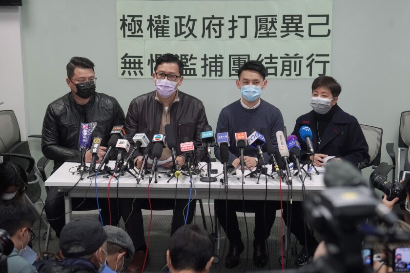 Former Democratic Party legislators Andrew Wan, left, Lam Cheuk-ting, second left, and Helena Wong, right, attend a press conference after being released on bail in Hong Kong, Friday, Jan. 8, 2021. Some former Hong Kong legislators and pro-democracy activists were released on bail late Thursday, after being arrested under Hong Kong's national security law as part of Wednesday's mass arrests of 53 people. The Chinese in the background reads "Totalitarian government suppresses dissidents, fearless of indiscriminate arrest, we walk forward together." (AP Photo/Kin Cheung)