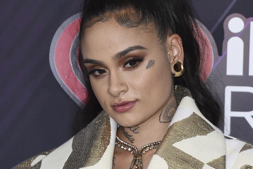Kehlani poses for pictures wearing a gold and white jacket
