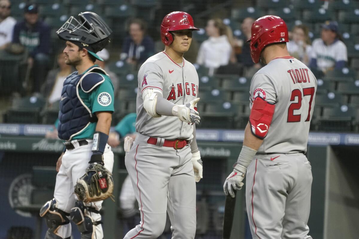 The Angels' Shohei Ohtani, center, is greeted by teammate Mike Trout after Ohtani homered in the third inning April 30, 2021.