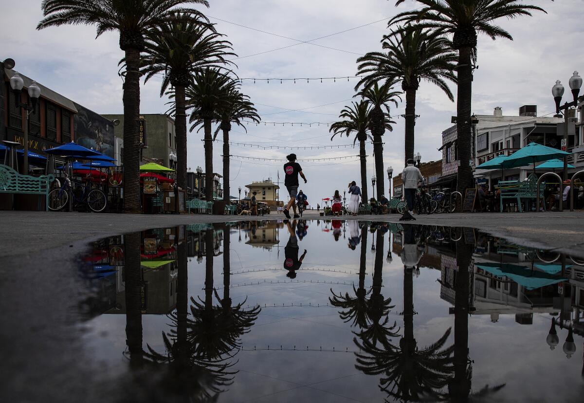 A pedestrian is reflected in a puddle in Hermosa Beach on Monday after rain passed through the area.