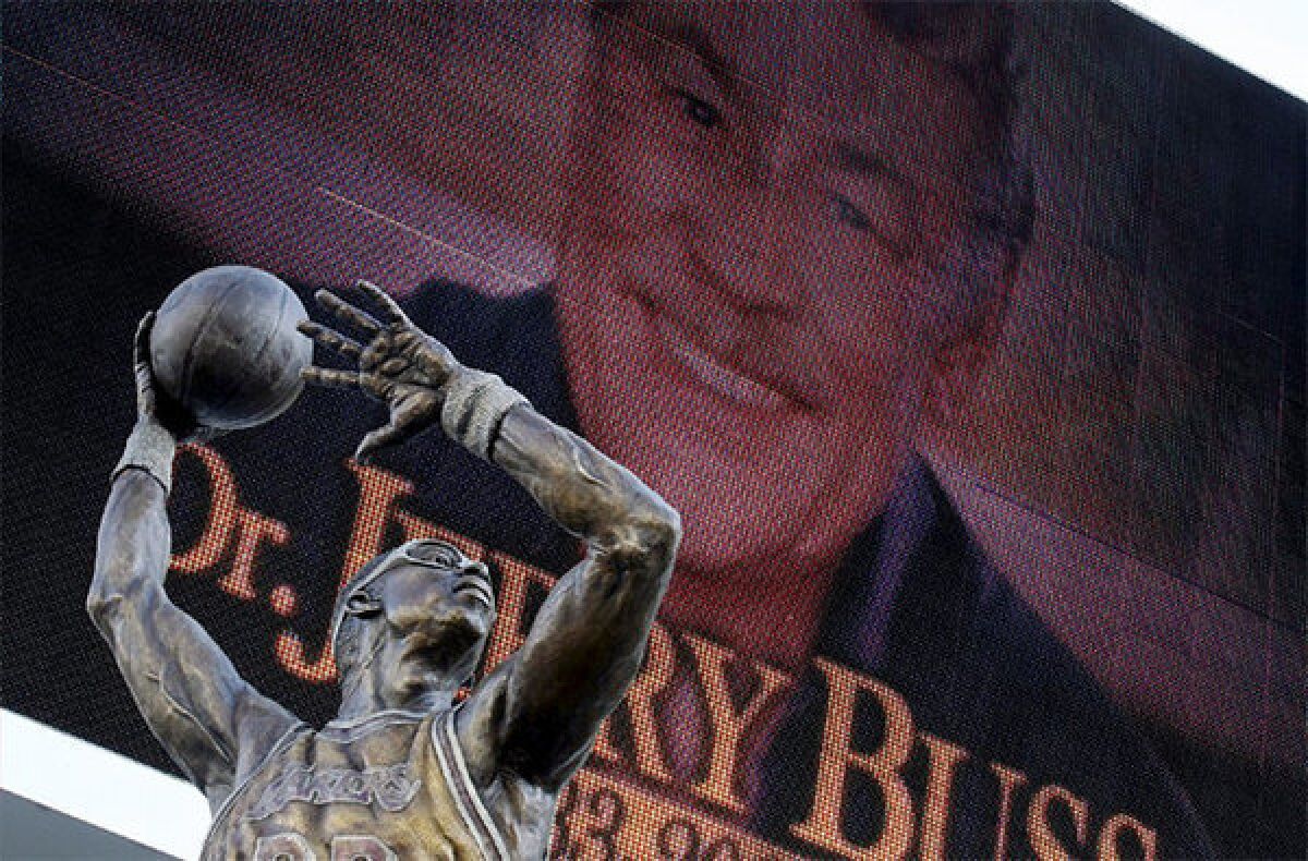 An image of Jerry Buss looks down on the statue of Kareem Abdul-Jabbar as people gathered at L.A. Live for a memorial service for Buss.