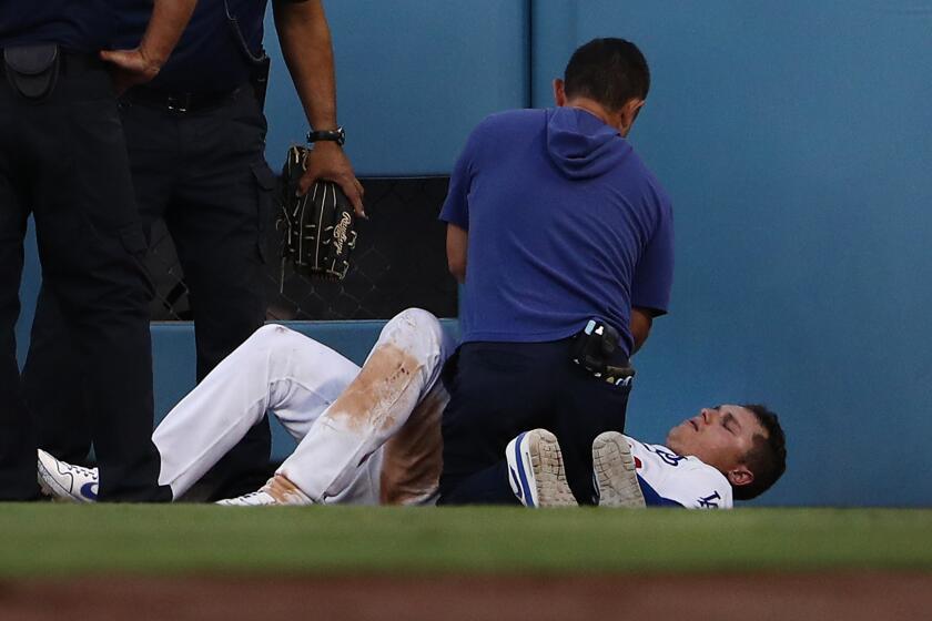LOS ANGELES, CALIFORNIA - SEPTEMBER 02: Joc Pederson #31 of the Los Angeles Dodgers lays on the field and is attended to by a team trainer after Pederson hit the right field wall while catching a fly ball in the fifth inning of the MLB game against the Colorado Rockies at Dodger Stadium on September 02, 2019 in Los Angeles, California. (Photo by Victor Decolongon/Getty Images)