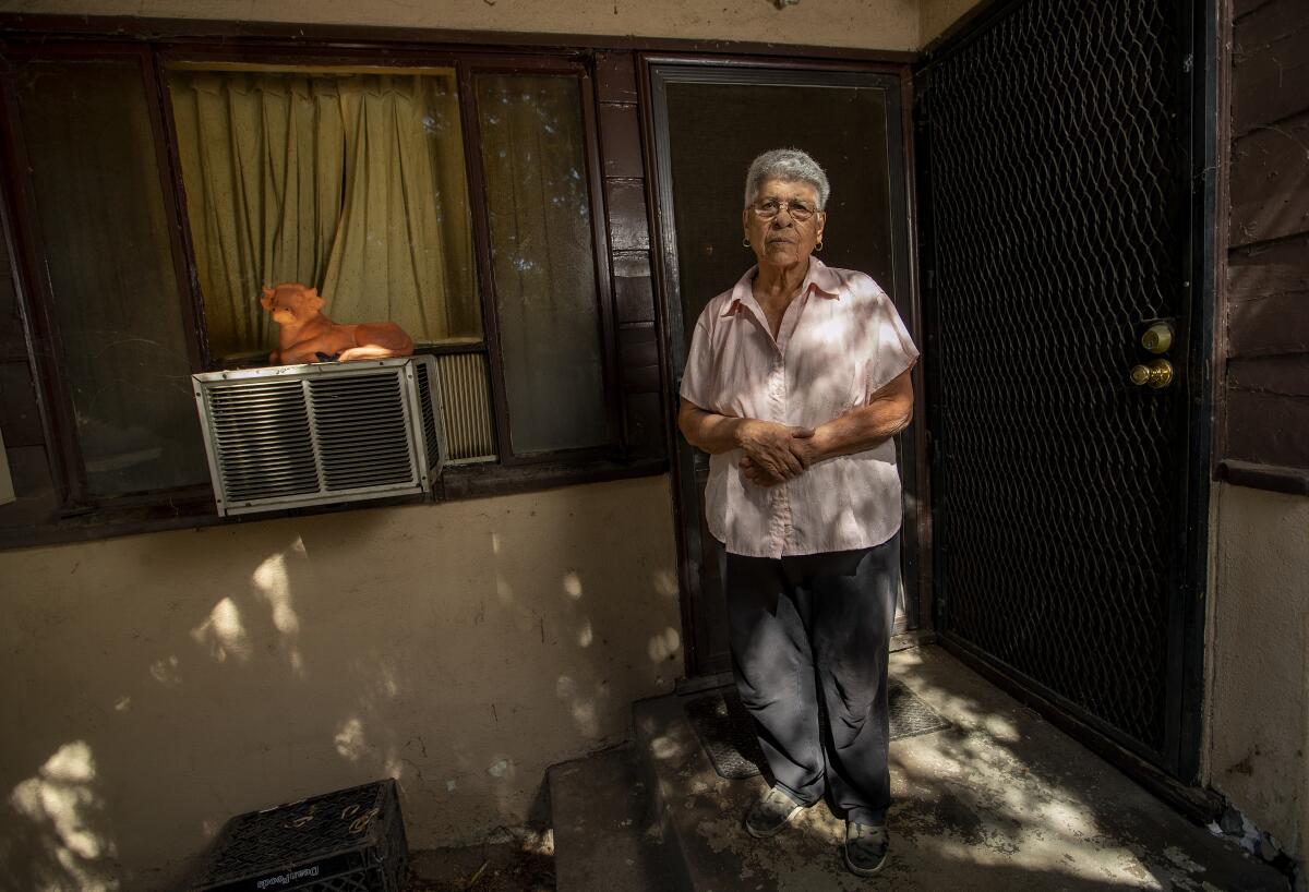 A woman stands outside an apartment front door