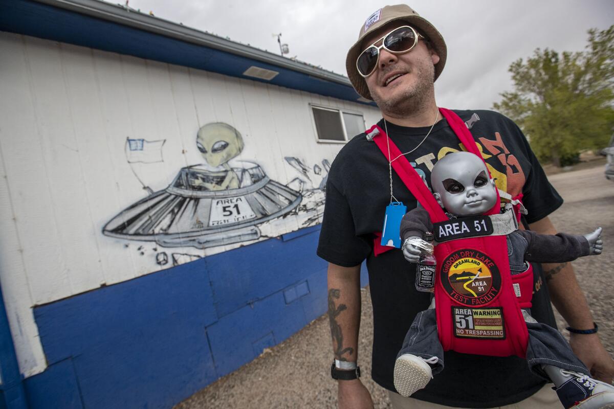 Alien enthusiast Rob Kulas of Chicago carries an alien baby doll around the Little A'Le'Inn grounds in the Area 51-adjacent town of Rachel, Nev.