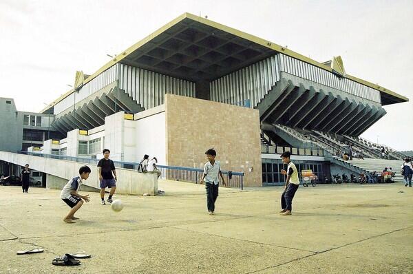 Children play soccer outside the national stadium designed by Cambodian architect Vann Molyvann in Phnom Penh. Vann Molyvann was a key creative force behind many Cambodian landmarks.