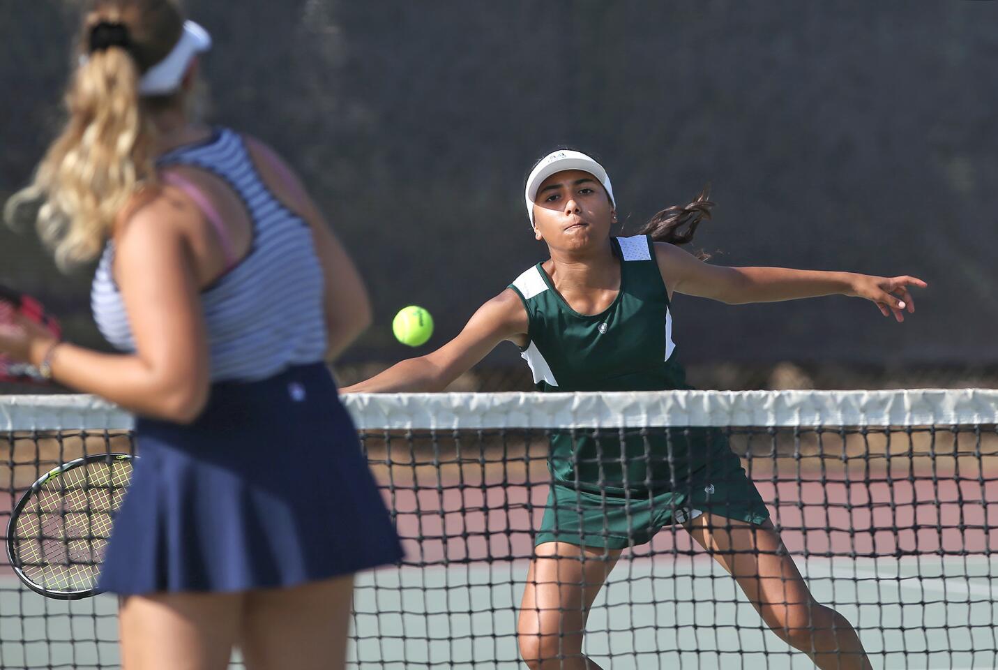 Costa Mesa High's Sophia Catania reaches for a volley as she and partner Megan Tran play in girlsâ€™ number two doubles match against Calvary Chapel in an Orange Coast League match at Costa Mesa Tennis Center on Tuesday.