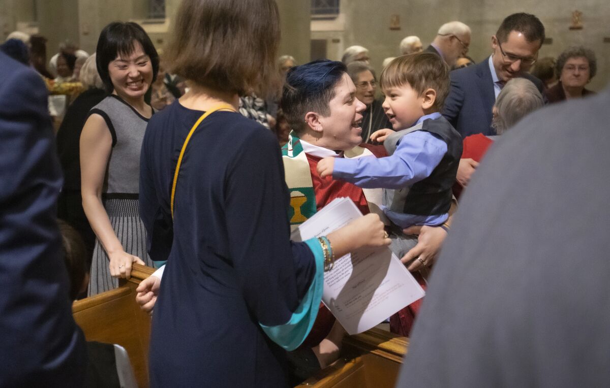 Pacyniak holds a nephew, Nicholas Pacyniak, one of numerous family members at the ordination ceremony. "We are very proud of Kori," said Basia Pacyniak, the new priest's mother.