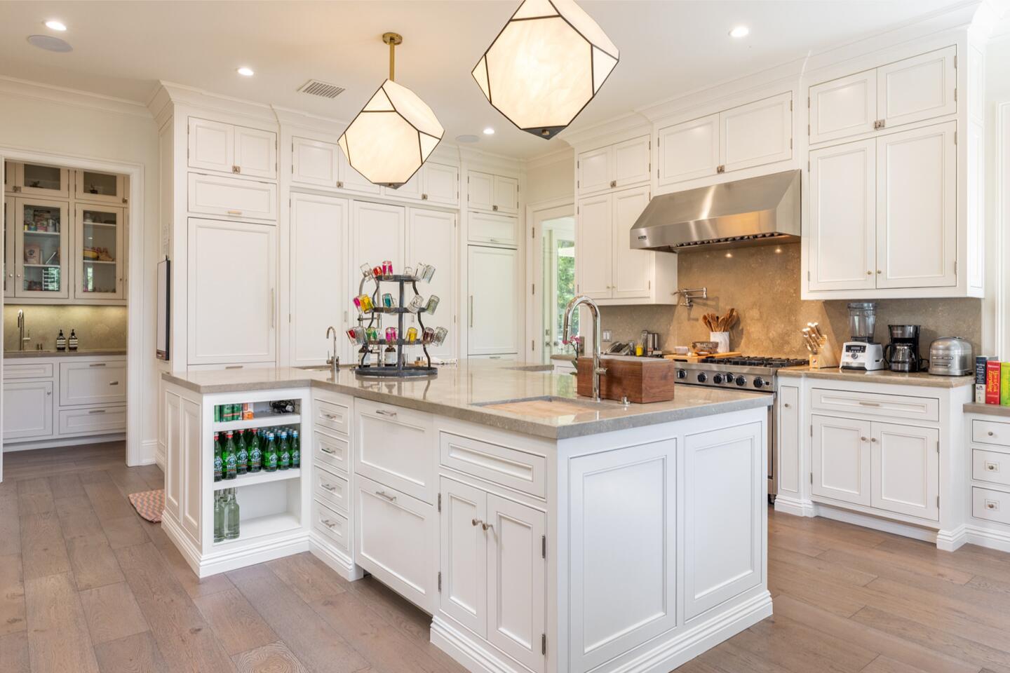 The kitchen is white with overhead lighting fixtures and an island.