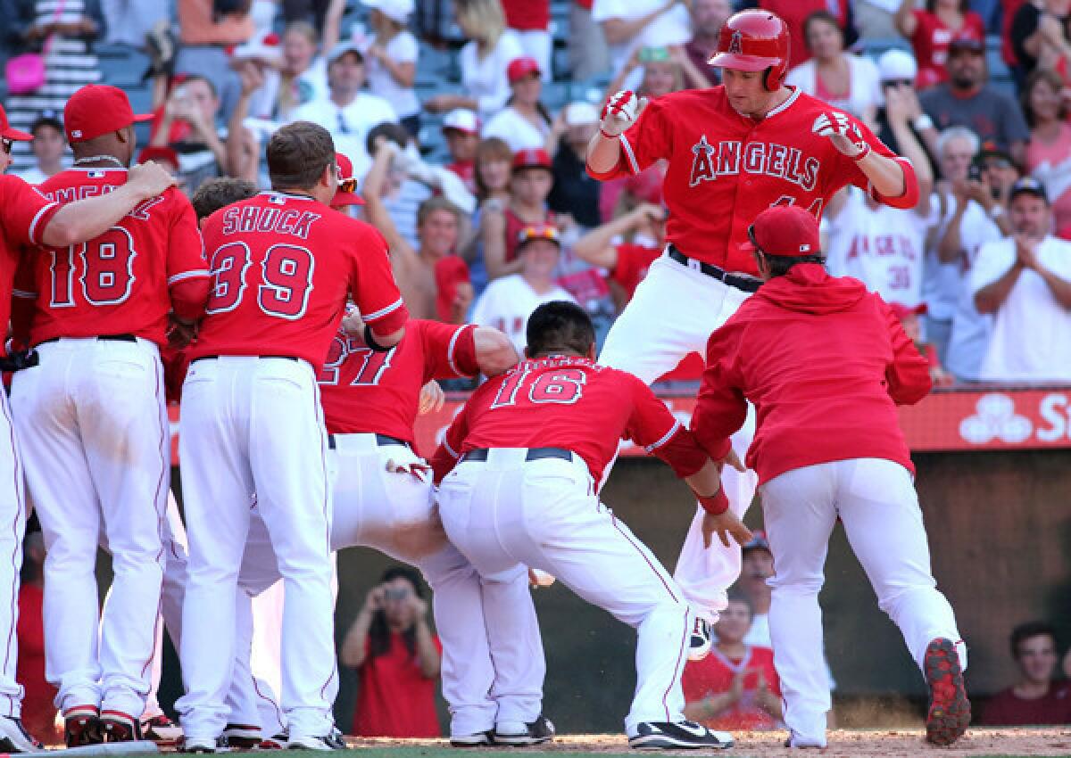 Angels designated hitter Mark Trumbo arrives at home plate with a leap into awaiting teammates after hitting the game-winning home run against the Tigers in the 13th inning Sunday afternoon in Anaheim.