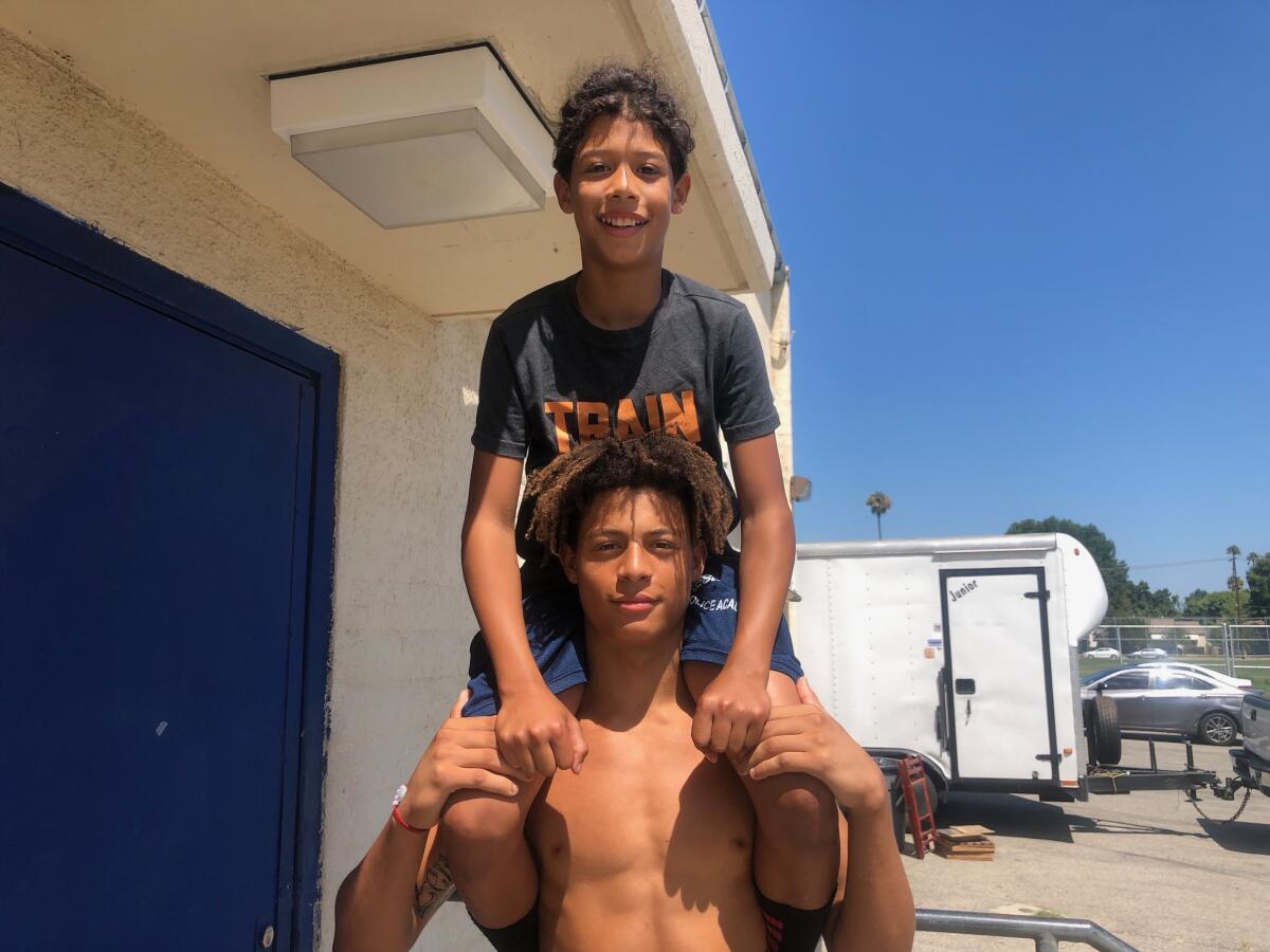 Reseda receiver Dranel Rhodes holds up his 12-year-old brother, Amari. They have an older brother who played for the Regents and are part of the tradition of younger brothers staying in the Reseda program.