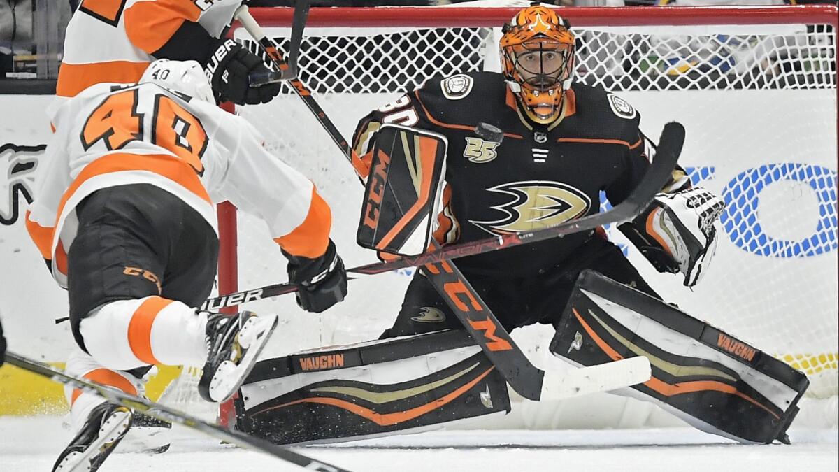 Ducks goaltender Ryan Miller stops a shot as Philadelphia's Jordan Weal trips in front of him.