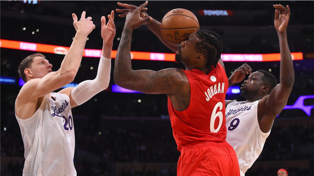 Lakers center Timofey Mozgov (20) and forward Luol Deng battle Clippers center DeAndre Jordan for a rebound during during their Christmas evening game.