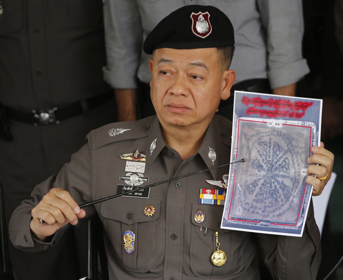 During a Nov. 17 news conference in Bangkok, a Thai police officer shows a picture of tattooed human skin that authorities say was found in a package mailed by two Americans sought in connection with a case involving stolen body parts.