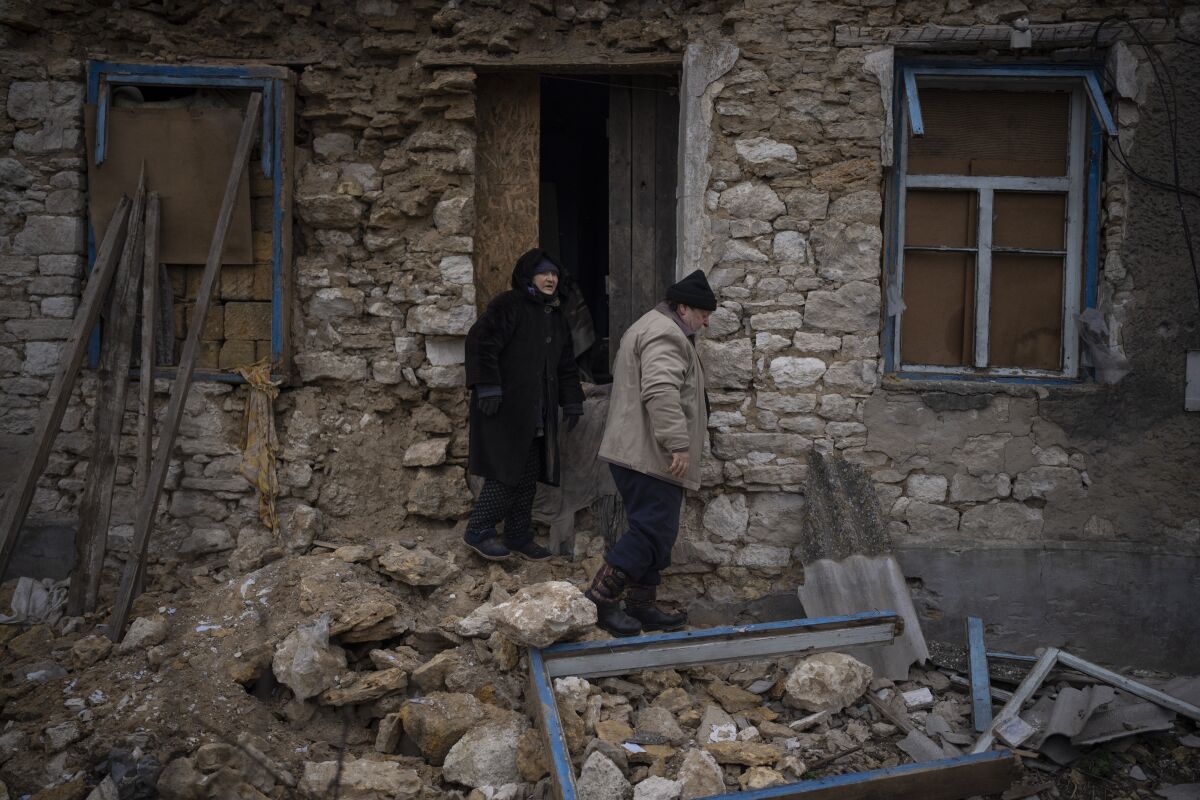 Ukrainian woman inspecting her damaged house