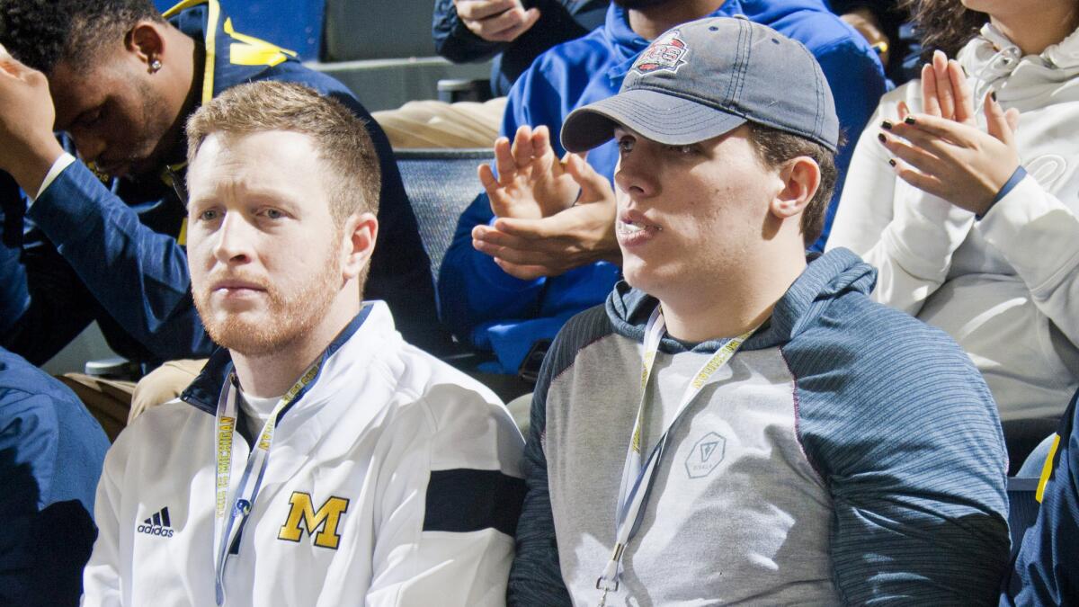 Michigan tight ends coach Jay Harbaugh, left, sits with high school recruit Chris Clark at a Wolverines basketball game against Northwestern in Ann Arbor, Mich., on Jan. 17.
