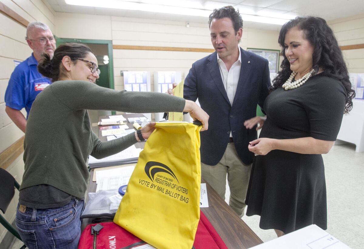Nathan Fletcher, candidate for San Diego County Supervisor, and his wife Lorena Gonzalez Fletcher turned in their absentee ballots to poll worker Kesia Estrada at the Colina del Sol recreation center on election day. Poll worker Mark Kunkee is at rear.