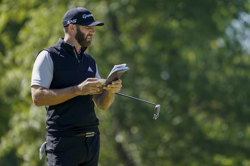 Dustin Johnson checks his notebook on the fifth green during the third round of the U.S. Open on Sept. 19, 2020.