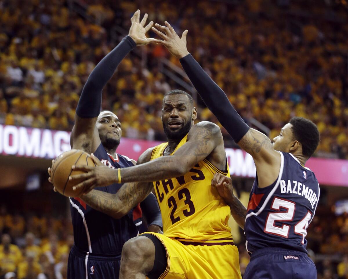 Cleveland forward LeBron James drives between Atlanta forward Paul Millsap, left, and guard Kent Bazemore, right, during the second half of Game 3 of the Eastern Conference finals.